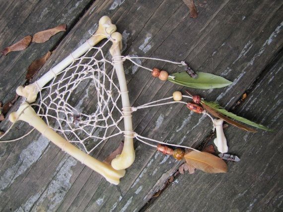 a piece of art made out of wood and string with leaves on it sitting on a wooden surface