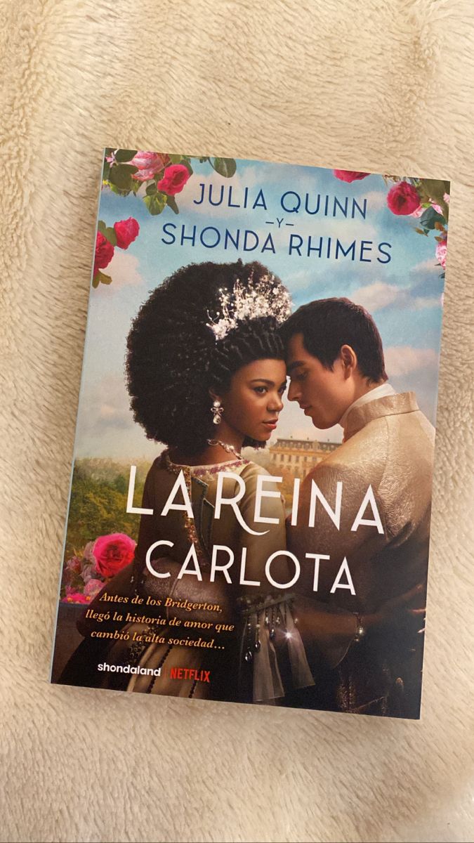 the book la reina carolina by julia quiinn shonda rhimes is laying on a bed