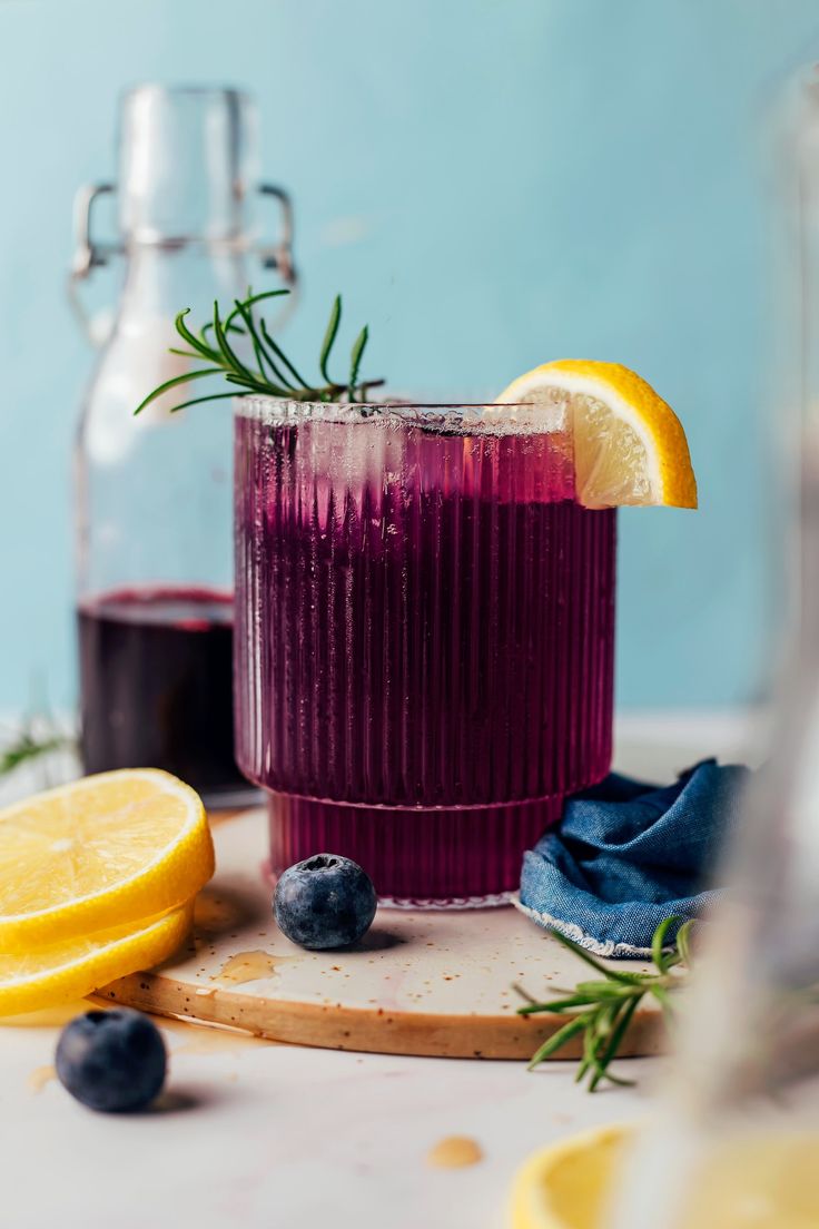 two glasses filled with blueberry lemonade and rosemary garnish