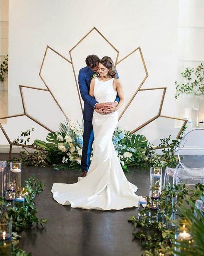 a bride and groom standing next to each other in front of an art deco backdrop