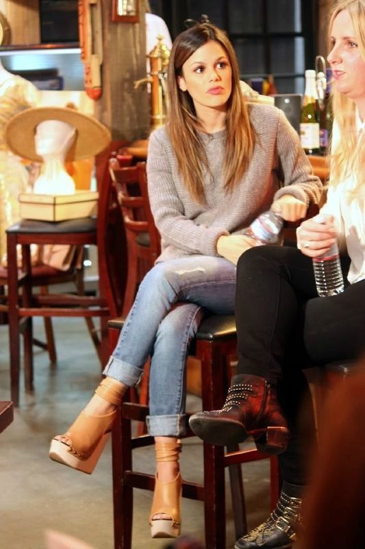 a man and woman sitting next to each other at a table with wine bottles in the background