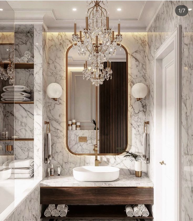 a bathroom with marble walls and flooring, a chandelier above the sink