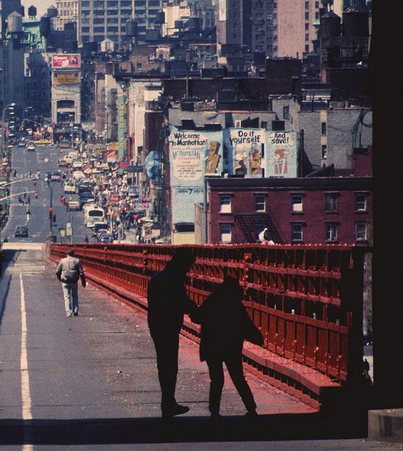 two people walking across a bridge in the city