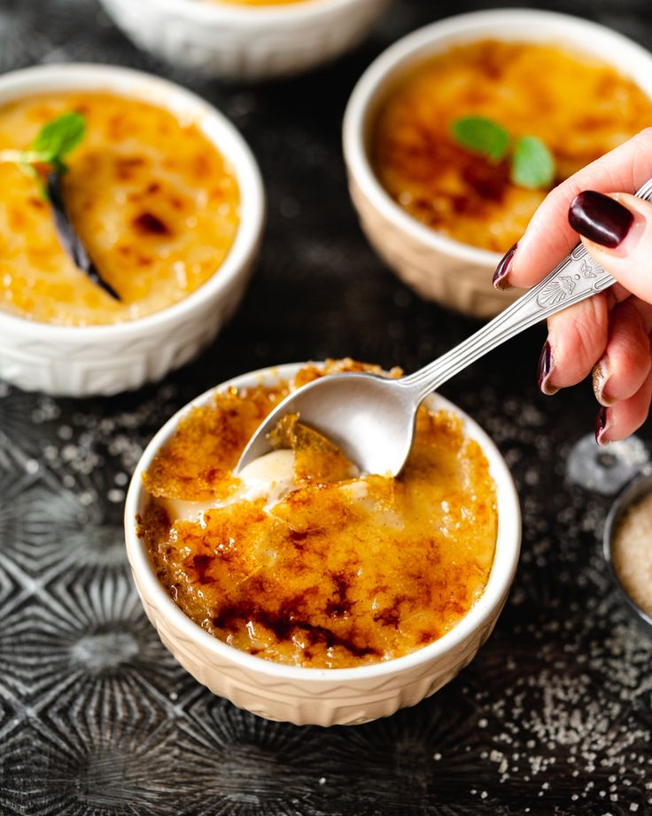 a person holding a spoon over some food in small bowls with other dishes behind them