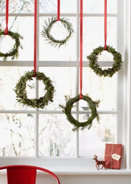 christmas wreaths hanging on the window sill in front of a red chair and presents