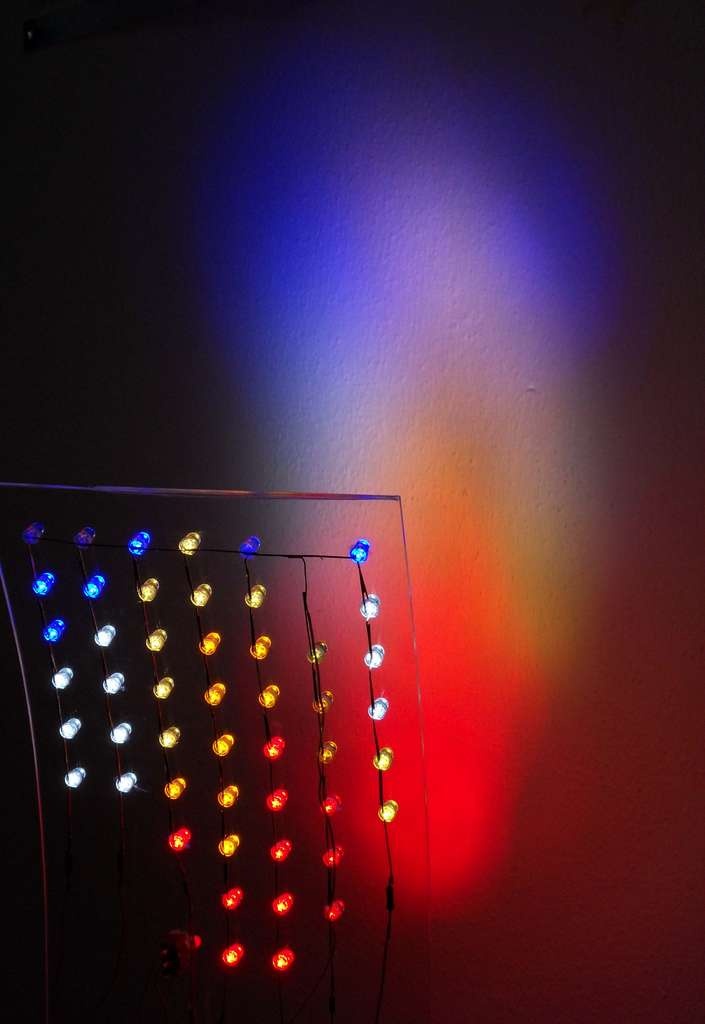 a wall with some lights on it and one light is red, white and blue