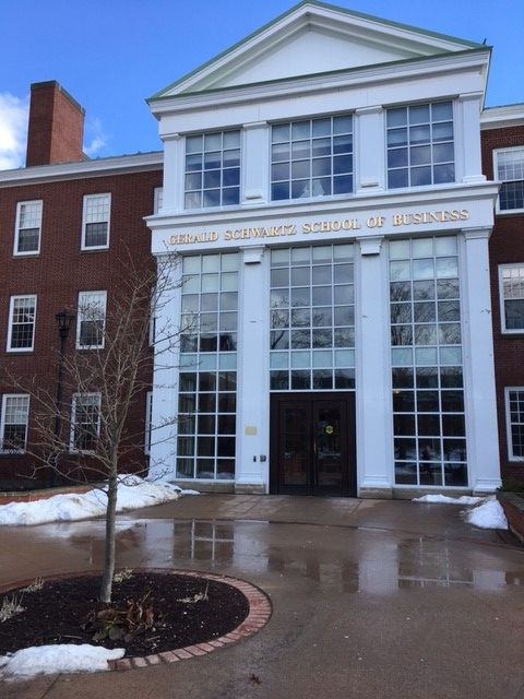 an empty building with snow on the ground and two trees in front of it,