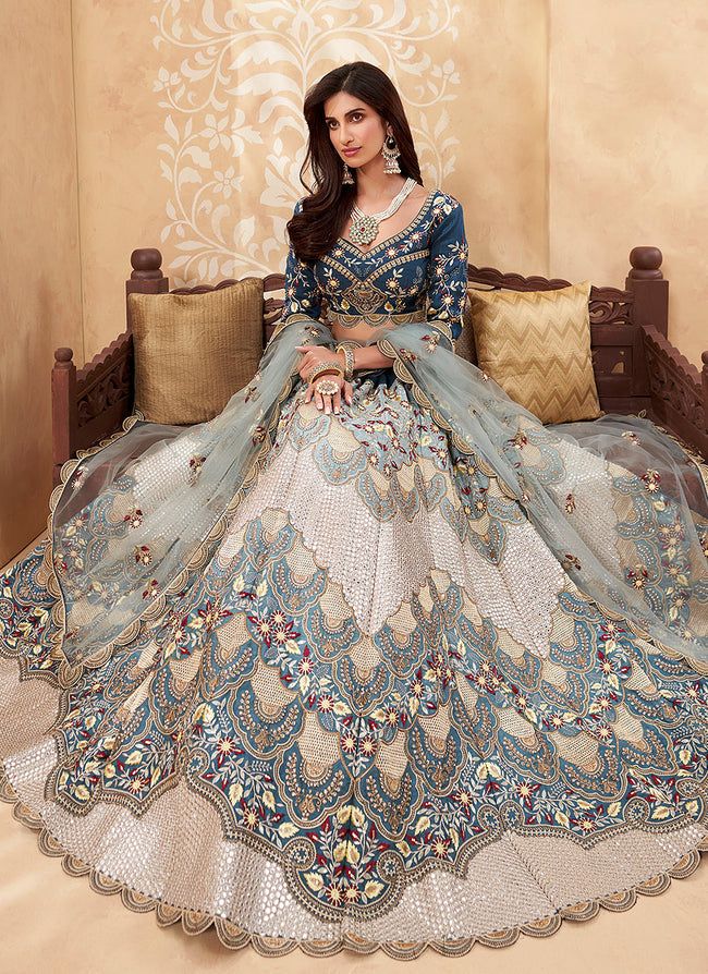 a woman sitting on top of a couch wearing a blue and white dress with intricate designs