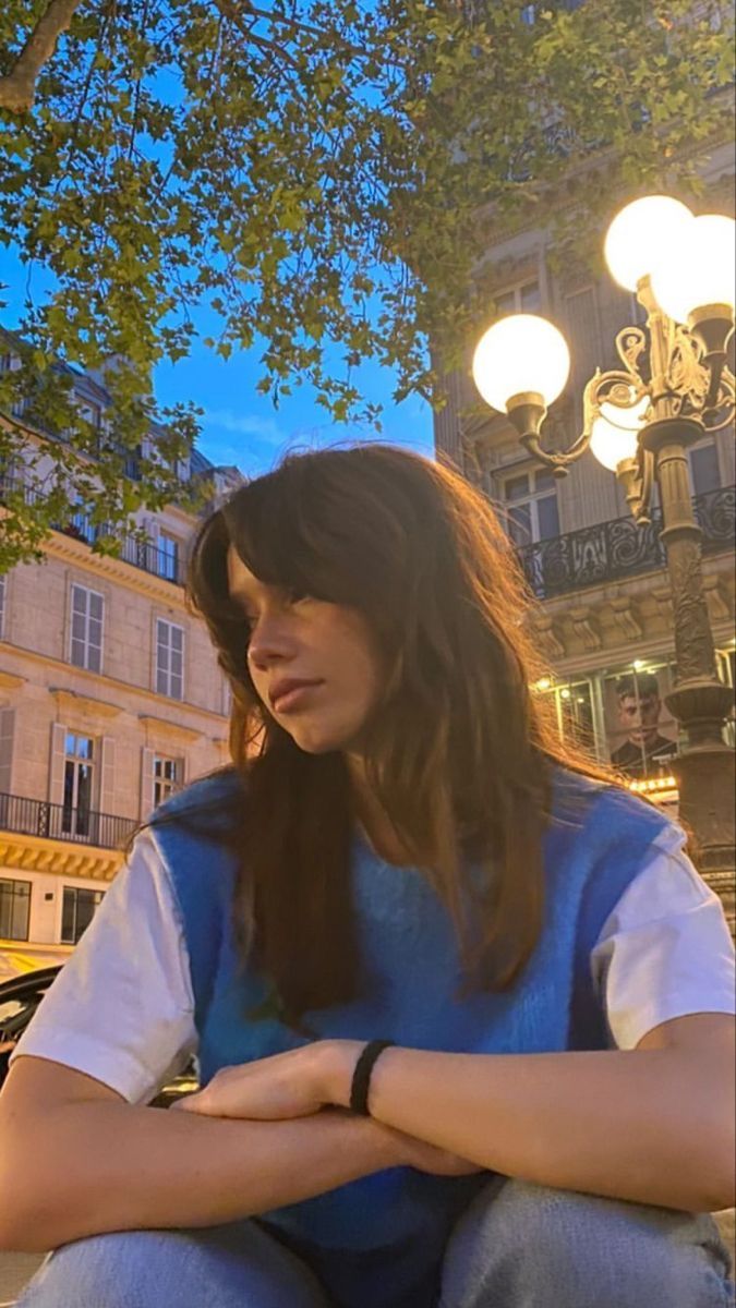 a woman sitting on the ground in front of a street light with her arms crossed