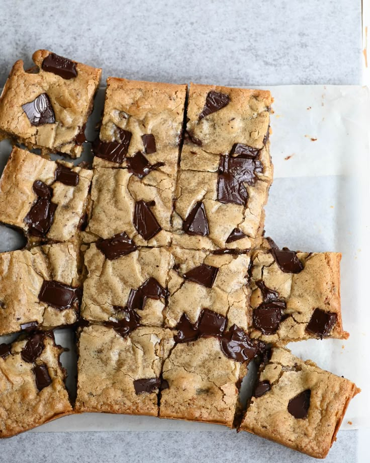 chocolate chip cookie bars cut into squares on a piece of parchment paper, ready to be eaten