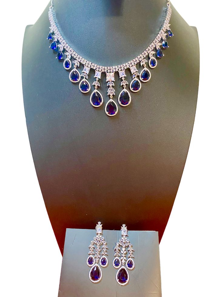 Add some sparkle to any occasion with our CZ American Diamond Necklace. Perfect for weddings, parties, or as a gift for her. This stunning necklace, made with beautiful bluestones, will elevate any outfit like sarees, gowns, or lehengas. Make a statement with this beautiful and versatile piece. This jewellery set includes a necklace and matching earrings. Jewellery Care- Keep the jewellery dry, avoid contact with perfumes and water. Elegant Blue Necklace For Reception, Elegant Blue Necklace For Receptions, Blue Hand Set Necklace For Diwali, Elegant Blue Jewelry Sets For Diwali, Bollywood Style Blue Jewelry Sets For Party, Blue Bollywood Jewelry For Reception, Bollywood Blue Bridal Necklace Hand Set, Elegant Blue Kundan Necklace For Reception, Blue Stone Work Jewelry For Reception