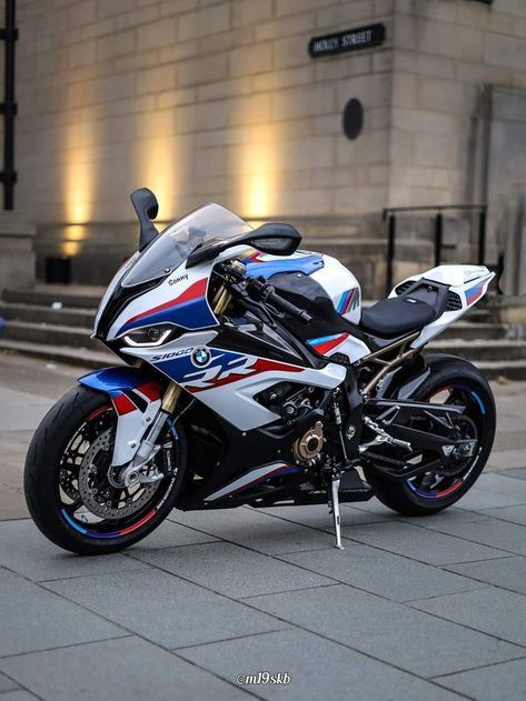 a white and blue motorcycle parked in front of a building with lights on it's side