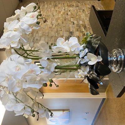 a vase with white flowers sitting on top of a counter