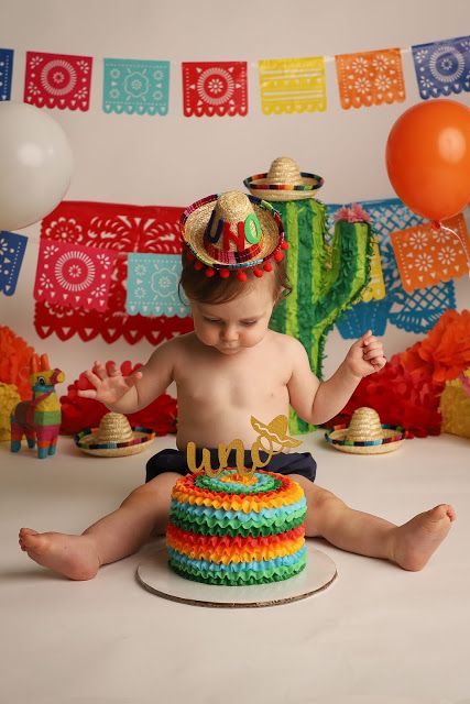 a baby sitting on the floor in front of a cake