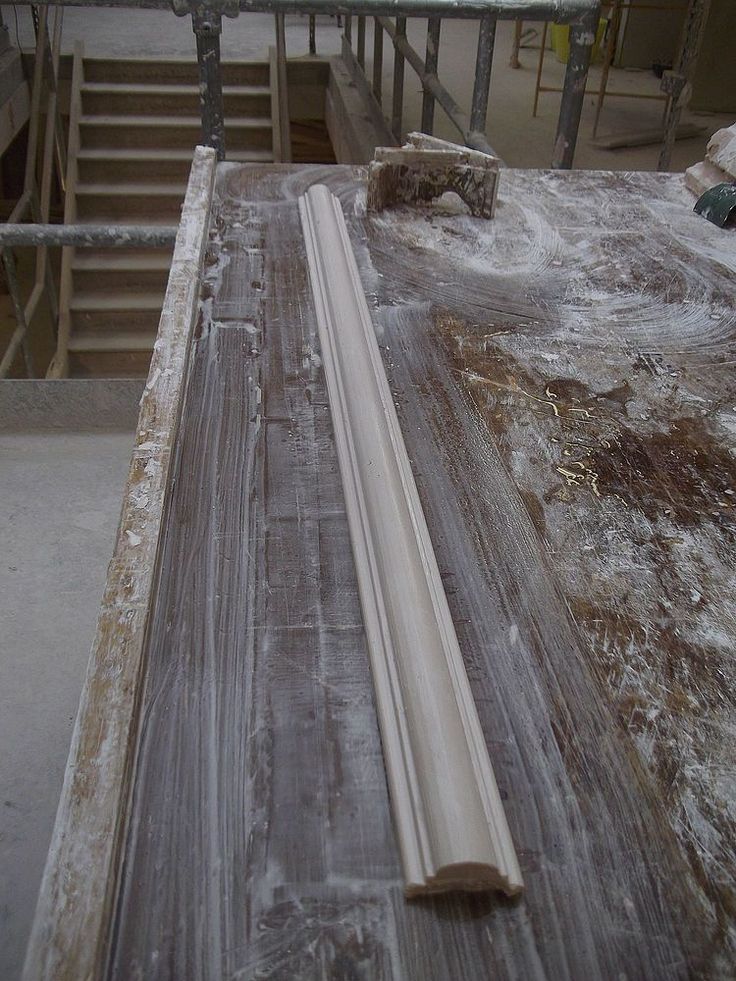 an unfinished piece of wood sitting on top of a wooden floor next to some stairs