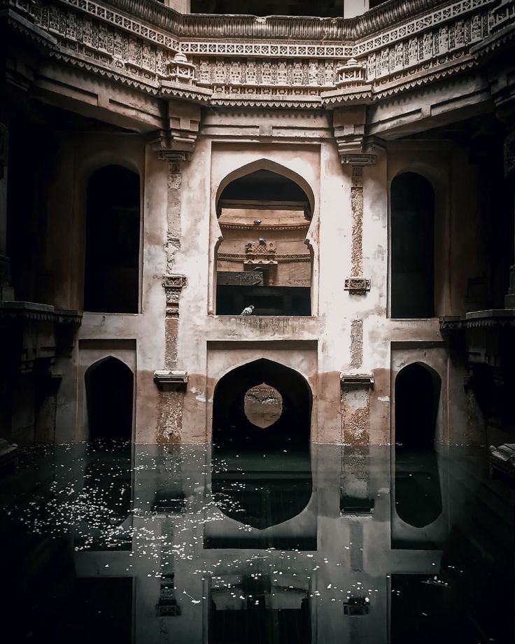 an old building with water in the middle and windows on each side, reflecting light