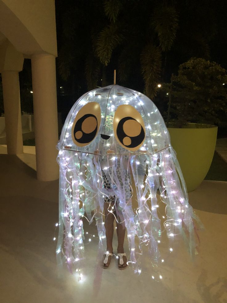 a person standing in front of a light up jellyfish with lights on it's head