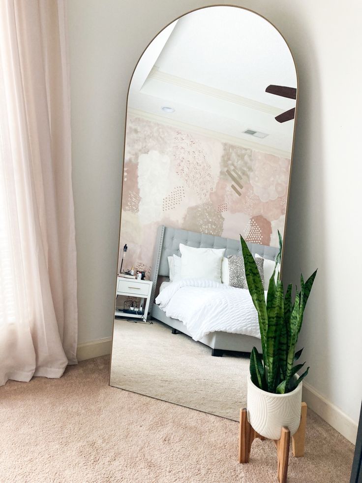 a bedroom with a large mirror on the wall and a plant in front of it