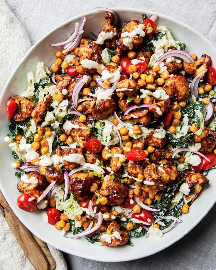 a white plate topped with chickpeas and red onion salad next to a wooden spoon