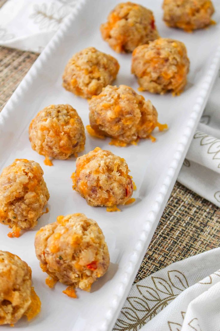 a white plate topped with meatballs on top of a cloth covered table next to napkins