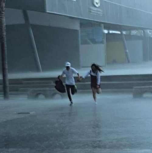 two people running in the rain holding hands