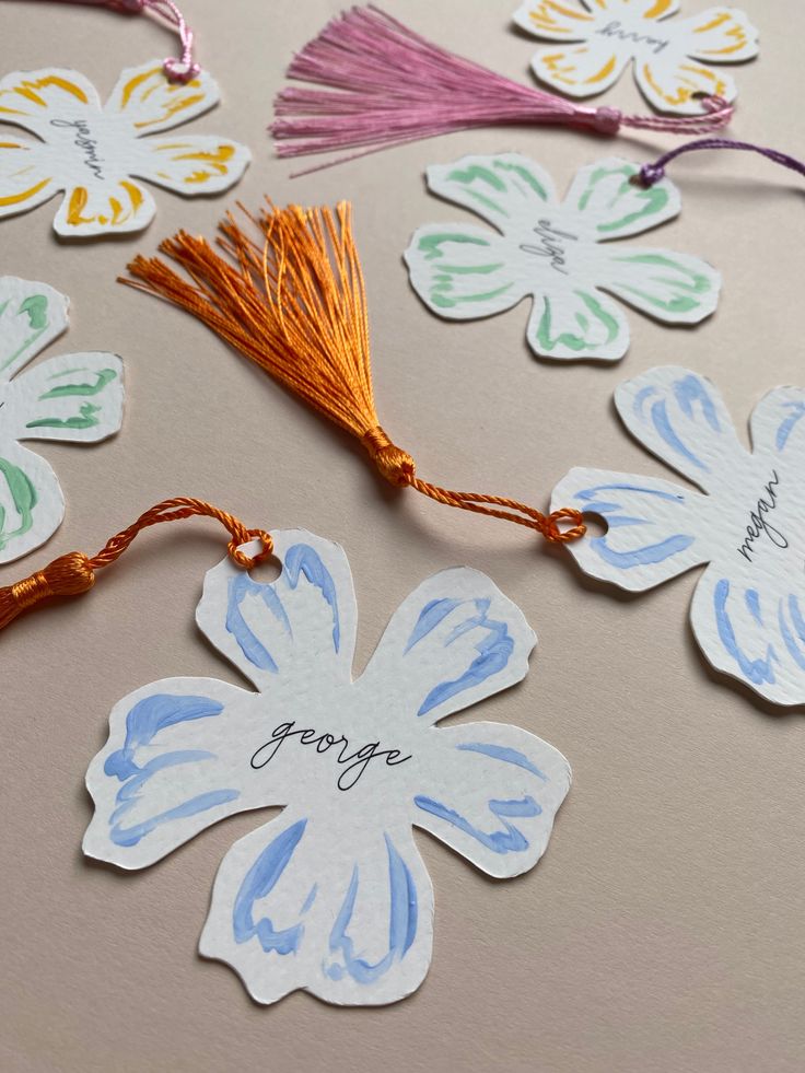 several flower shaped tags with tassels on them