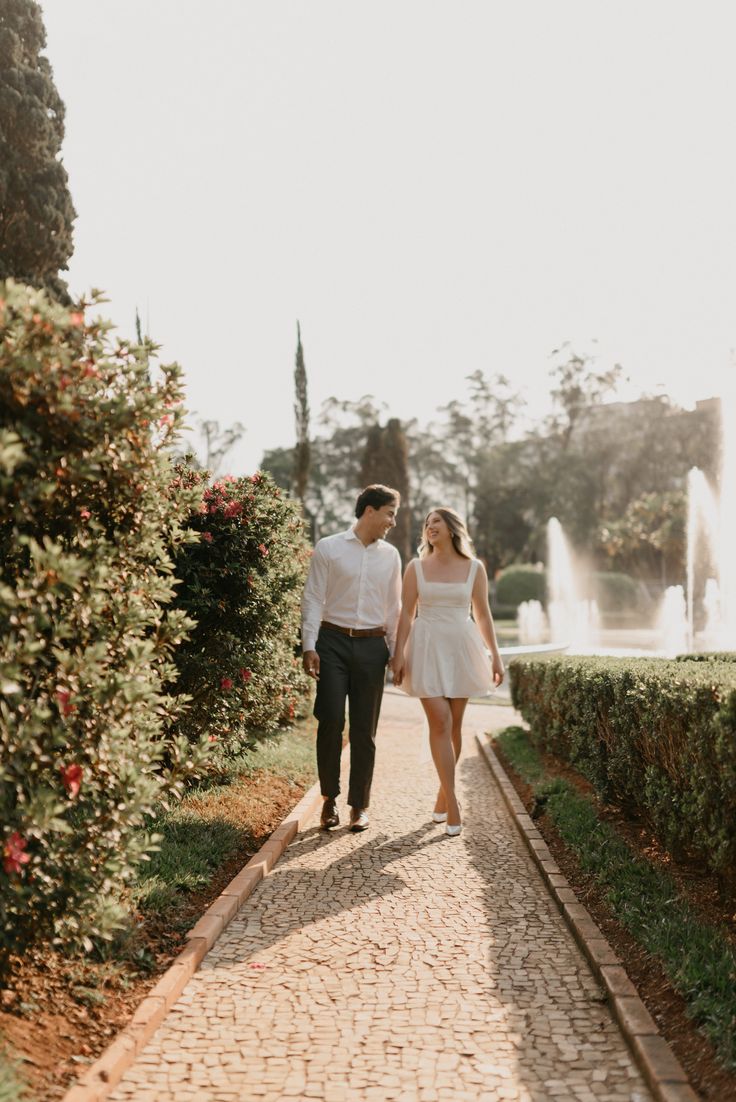 a man and woman walking down a path holding hands