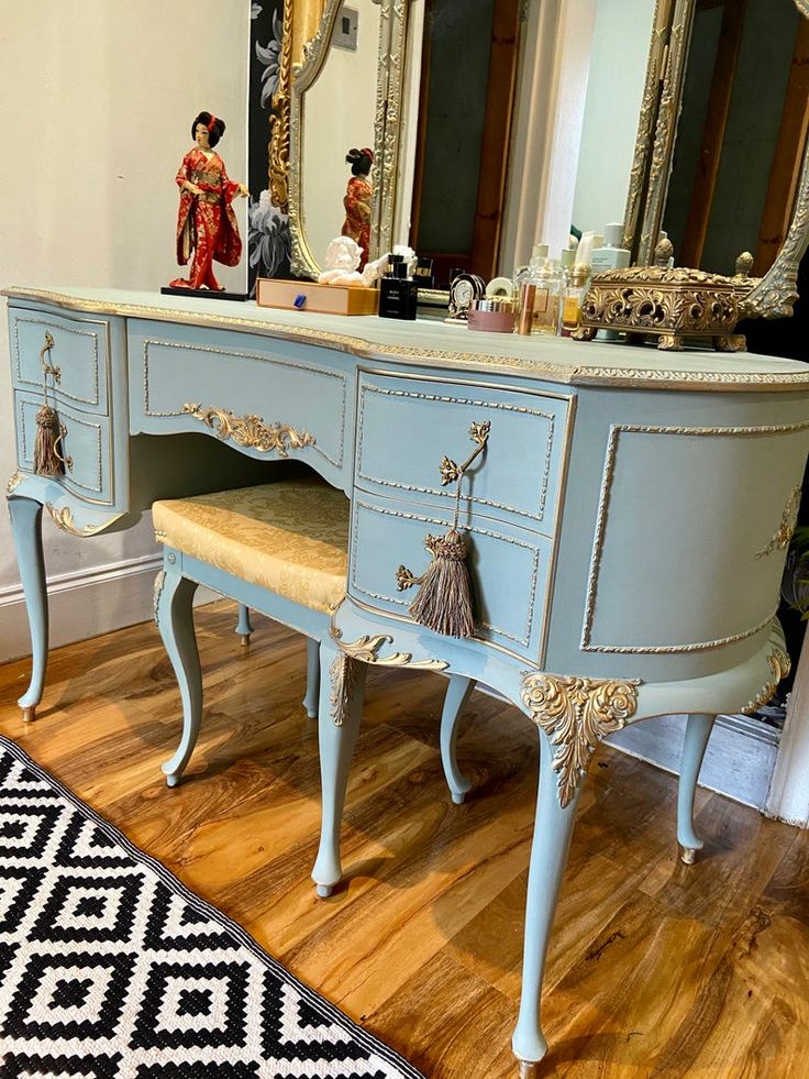 a blue vanity with a mirror and figurines on it in a living room