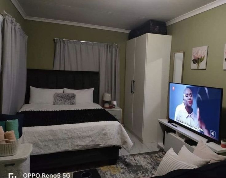 a bed room with a neatly made bed and a flat screen tv on the wall