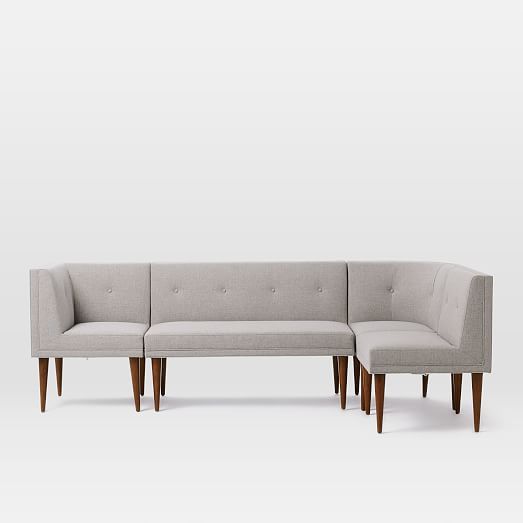 a gray couch sitting on top of a white floor next to a wooden frame chair