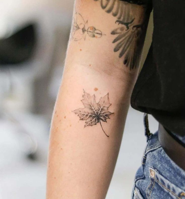 a woman's arm with a tattoo on it that has a leaf in the middle