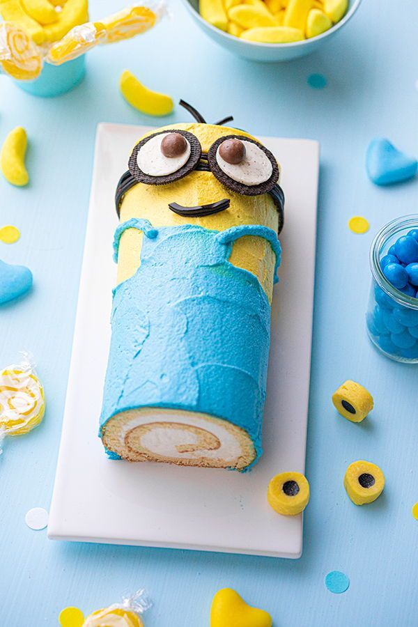 a cake shaped like a minion sitting on top of a white plate next to blue and yellow confetti