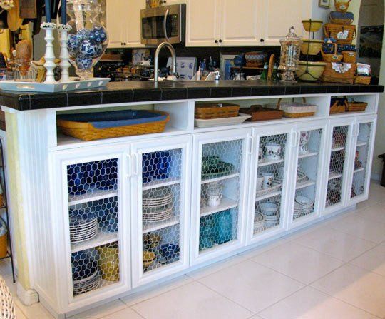 a kitchen with white cabinets and black counter top next to an island filled with dishes