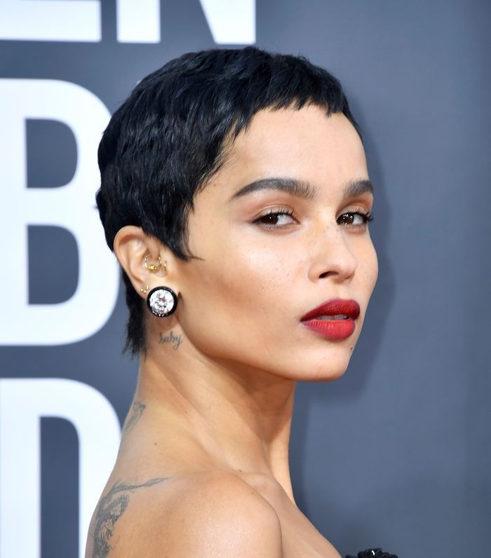 a close up of a person with tattoos on her chest and wearing earrings