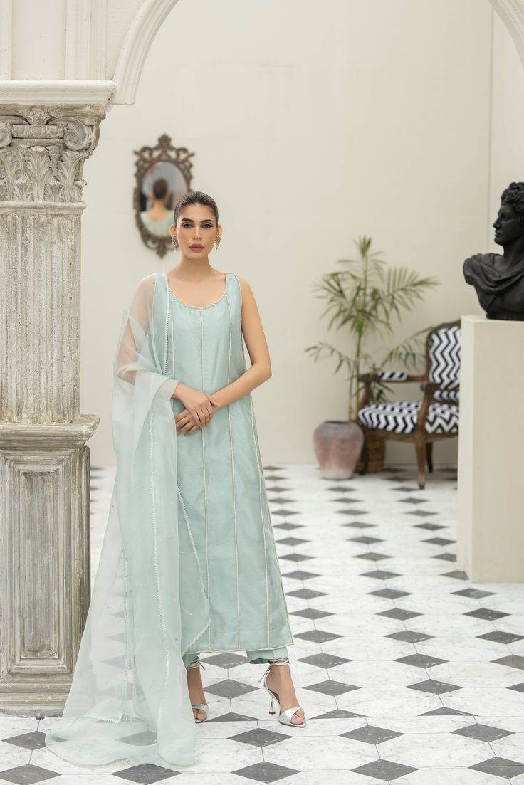 Meet our eye-catching Aqua-colored pure tissue long shirt hand worked in straight lines with pearls and zardozi and our signature big motif at the back of the shirt intricately handworked with resham, dabka, kora, sequins and beads. Paired with Rawsilk cigarette pants and a matching pure organza dupatta with a spray of handworked rosettes and pearls.