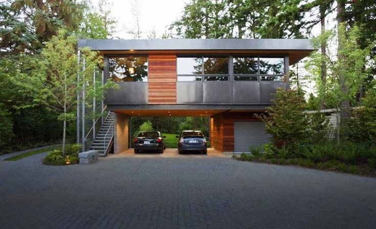 two cars are parked in front of a modern house with wood and metal sidings