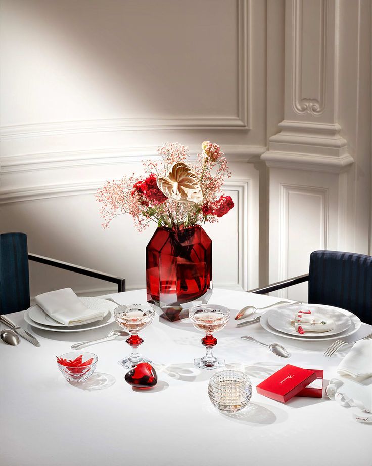 a white table topped with plates and vase filled with flowers