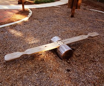 a piece of wood that is laying on the ground in front of a playground area