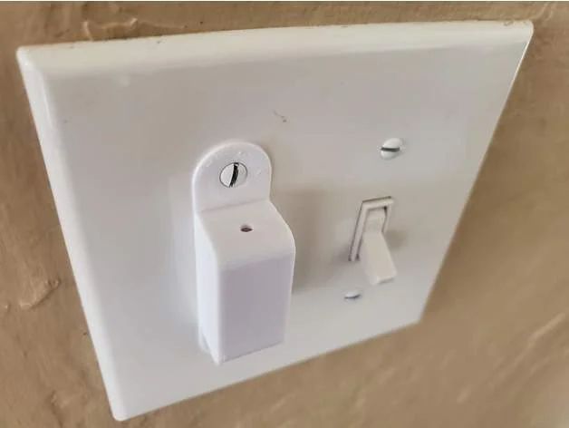 a white light switch sitting on top of a wooden floor next to a wall mounted outlet