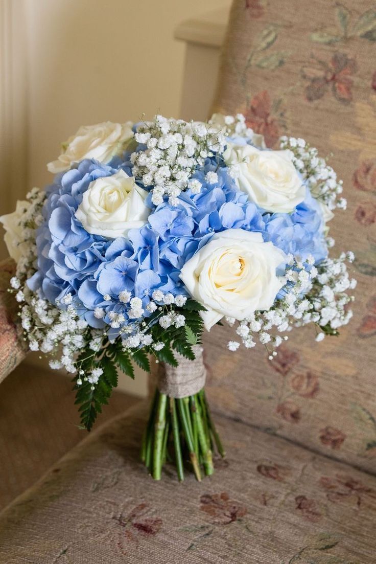 a bouquet of blue and white flowers sits on a chair in front of a couch