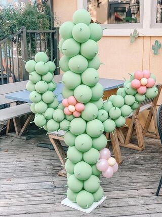 a large balloon cactus sitting on top of a wooden floor next to a table and chairs