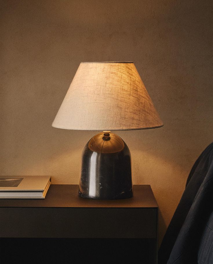 a lamp on a night stand next to a book