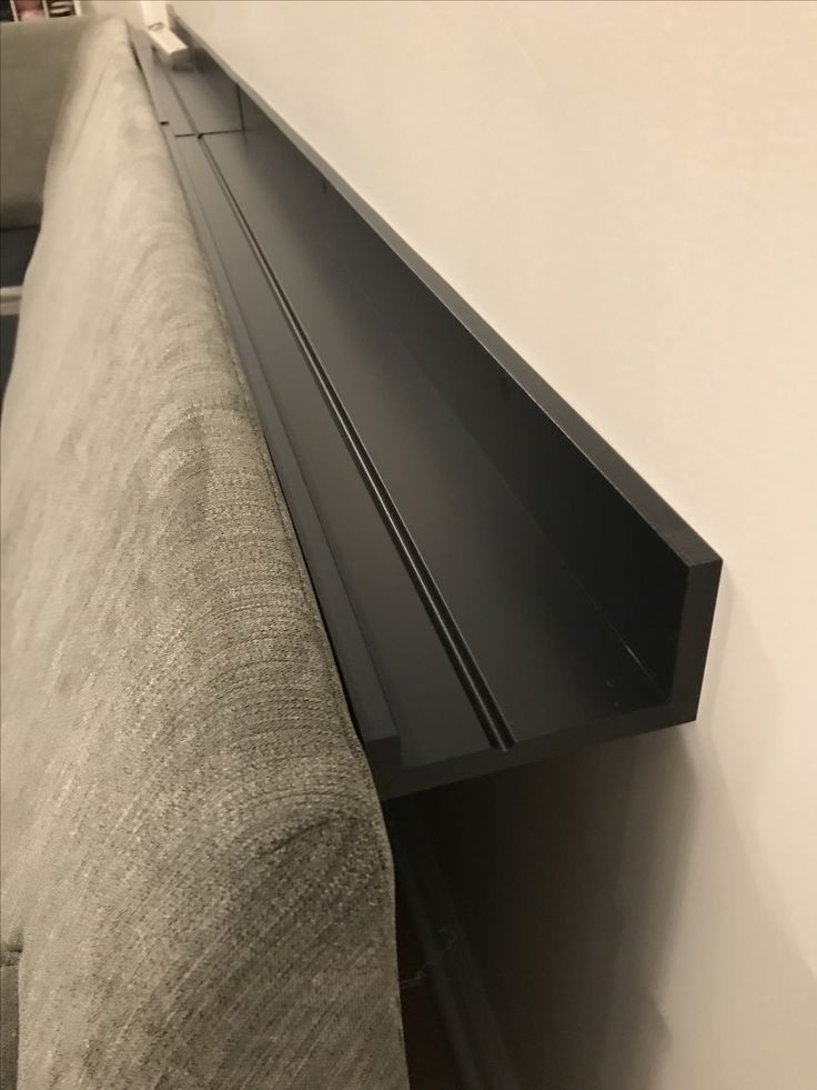 a close up view of a black shelf on the side of a couch in a living room