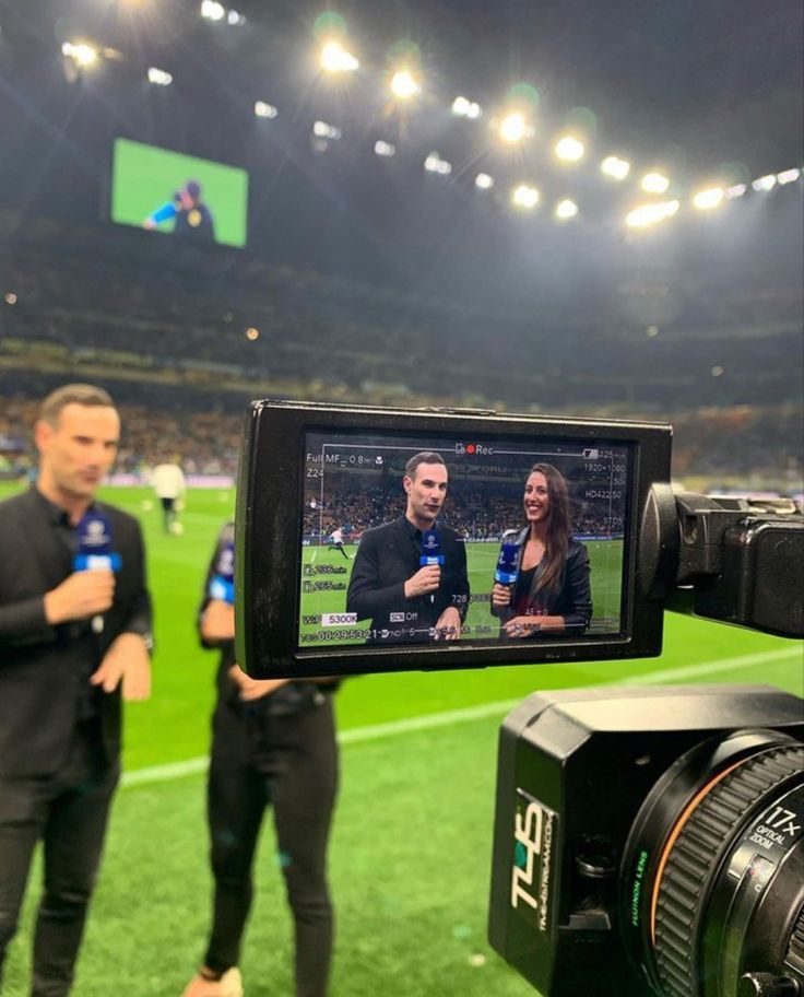 a camera is being used to record a soccer game with two people in the background