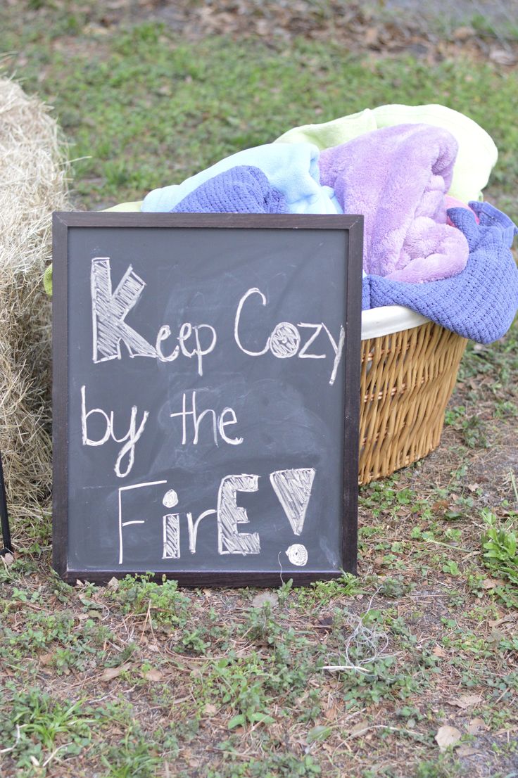 a sign that says keep cozy by the fire next to a basket full of blankets