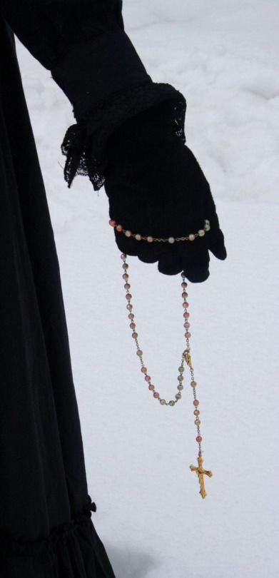 a person wearing black gloves and holding a rosary