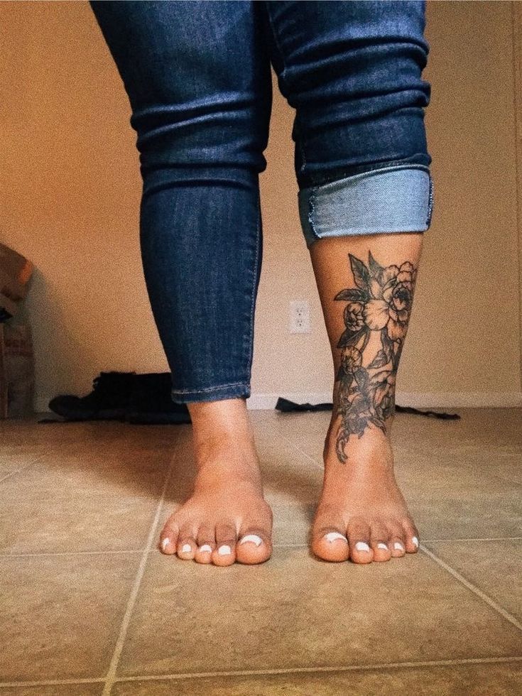 a person with a tattoo on their foot standing in front of a wall and floor