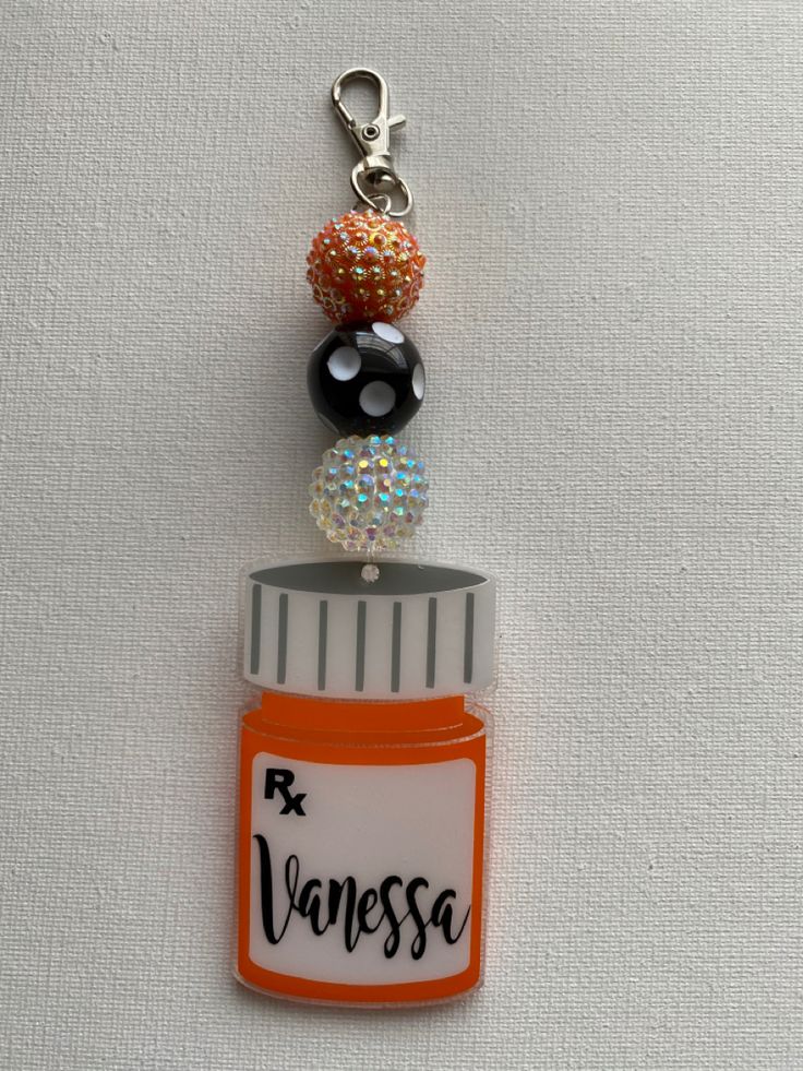 an orange bottle with some beads on it and a keychain attached to it