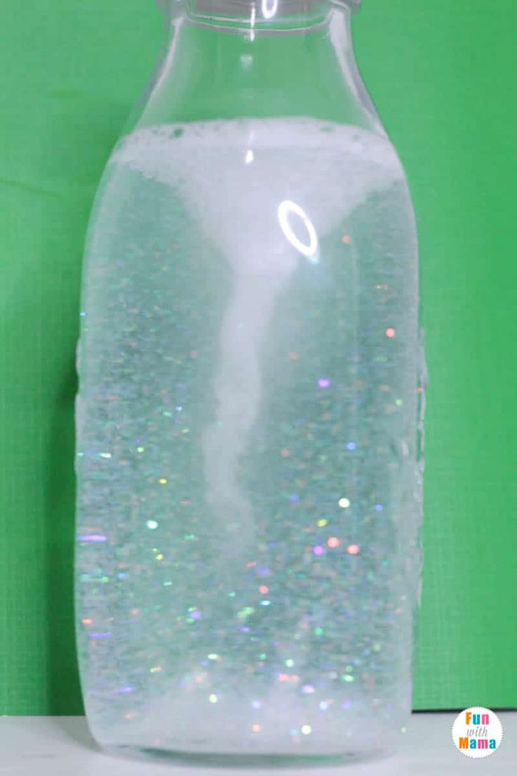 a glass bottle filled with liquid on top of a white counter next to a green wall