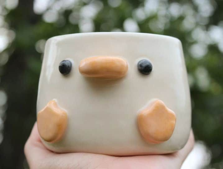 a hand holding a ceramic bird with two eyes